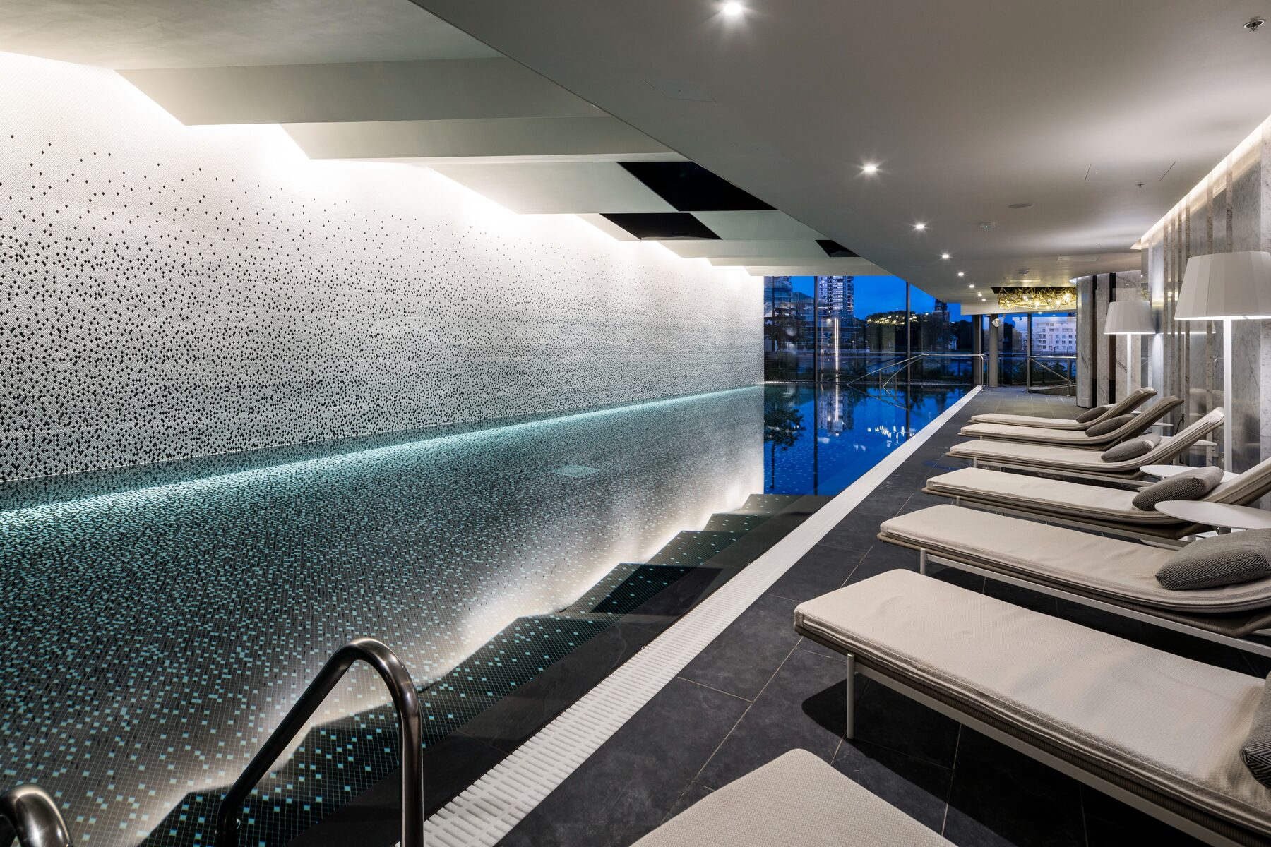 The residents’ swimming pool with loungers at dusk